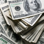 Stack of one hundred dollars notes on dollars background